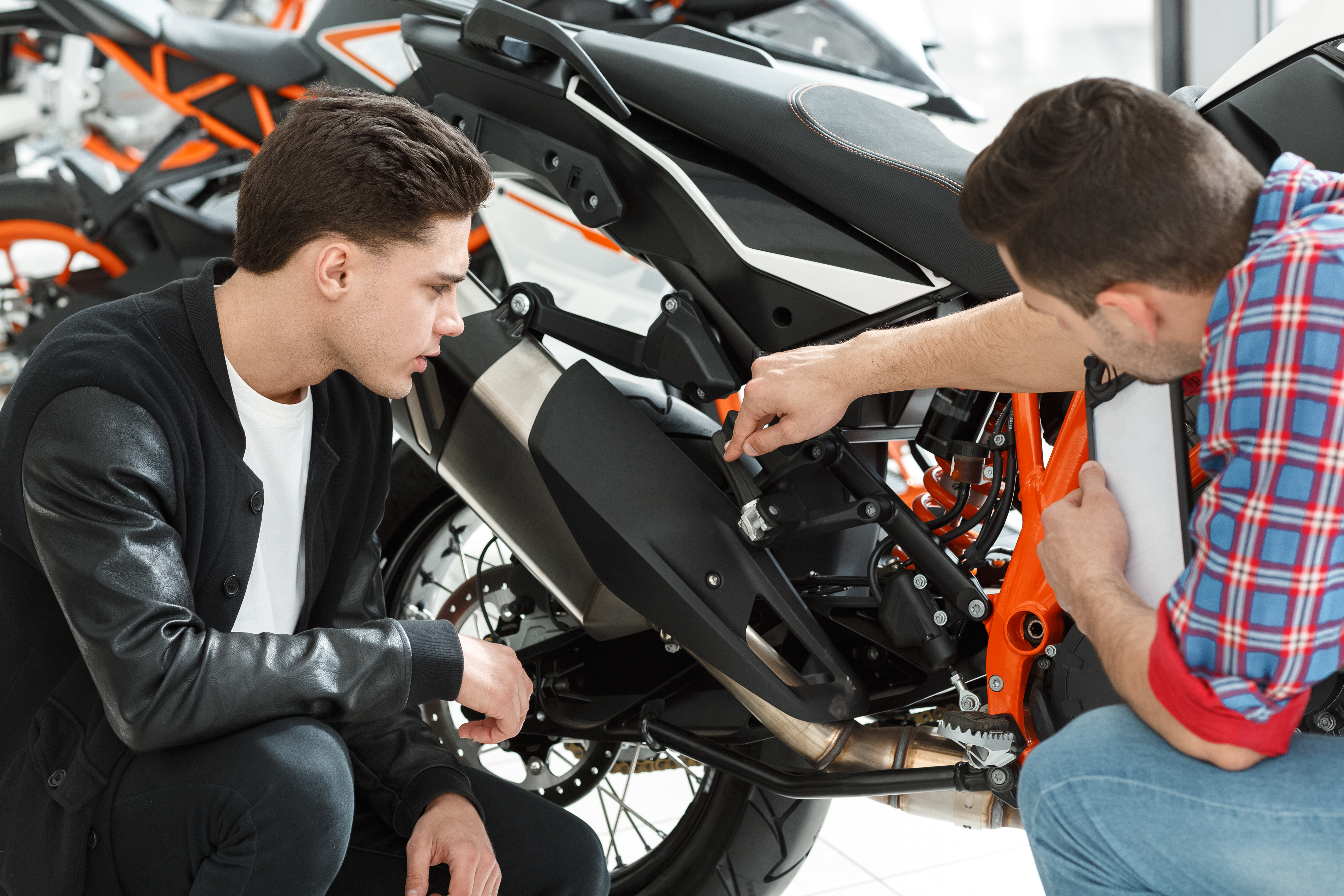 Ein schwarzes Motorrad wird von einem Gutachter für Motorräder und dem Besitzer des Motorrads begutachtet. 